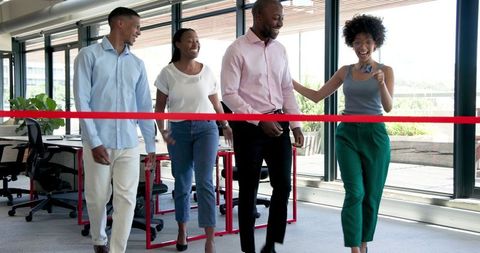 Diverse team celebrates new office opening with ribbon cutting
