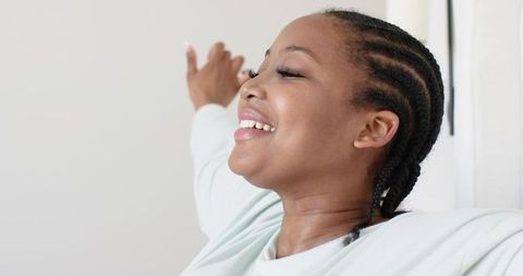 African american woman stretching and smiling in sunlit home interior expressing morning calm