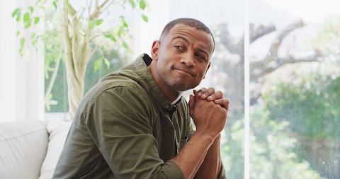 Thoughtful Biracial Man Relaxing at Home in Sunlit Living Room