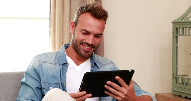 Handsome man on the sofa using tablet at home - Download Free Stock Photos Pikwizard.com