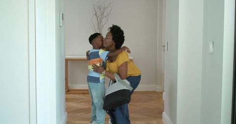 African american mother hugging son in home entryway conveying warm family reunion