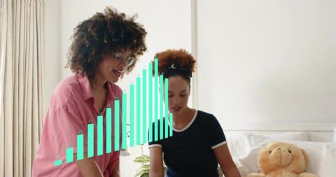 Women collaborating in bedroom while analyzing growth chart overlay with teddy bear
