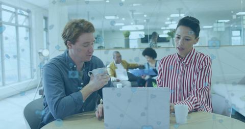 Diverse Professionals Discussing Over Laptop in Modern Office