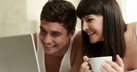 Couple Smiling While Viewing Laptop Screen in Domestic Setting