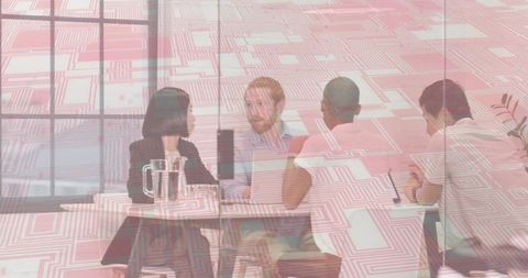 Modern team collaborating at office table with laptop and water pitcher, geometric glass