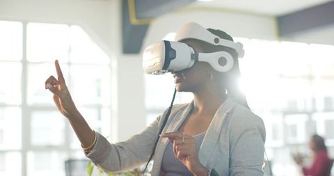 African American woman exploring virtual workspace with VR headset and gesture controls