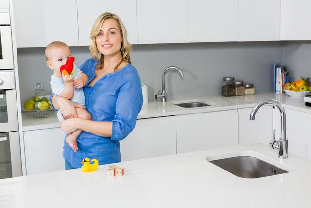 Smiling Mother Holding Baby Boy in Modern Kitchen at Home - Download Free Stock Photos Pikwizard.com