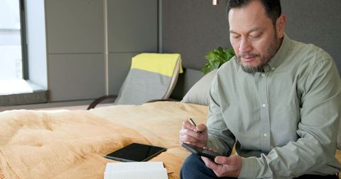 Senior man using tablet on bed with stylus for creative work