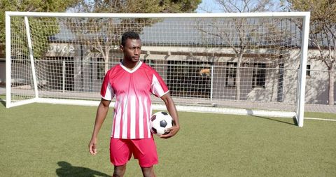Confident Soccer Player Holding Ball on Field
