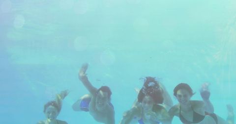 Friends joyfully swimming underwater in a pool