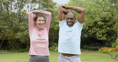 Smiling Couple Stretching Together in Tranquil Garden Setting