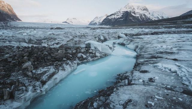 Carving turquoise meltwater through glacial valley with moraine and snow peaks
