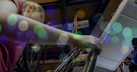 Focused woman adjusts bicycle wheel in workshop