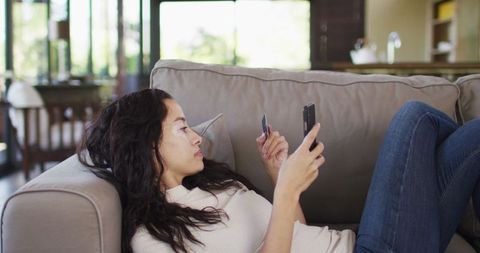 Woman Lying on Couch Making Online Purchase with Smartphone