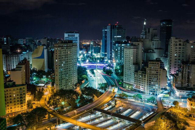 This vibrant image captures the stunning night view of São Paulo's cityscape, showcasing its brightly lit highways, imposing skyscrapers, and bustling urban life. Ideal for use in articles about urban development, travel destinations in Brazil, or the beauty of metropolitan cities at night. Perfect for websites, brochures, and marketing materials that focus on city living and architecture.