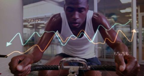 Cyclist powering through indoor bike session with digital performance graphs and metrics