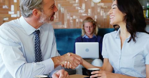 Business Colleagues Shaking Hands Over Coffee in Lounge Setting