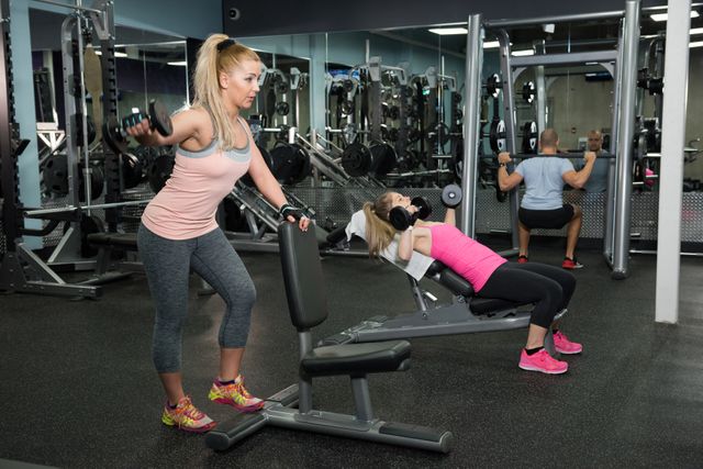 People working out in a modern gym, using various equipment for strength training. Ideal for promoting fitness centers, workout programs, health and wellness campaigns, and active lifestyle content.