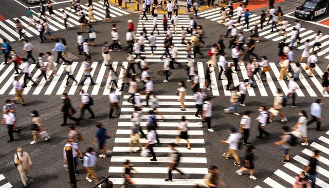 Busy urban crosswalk at major intersection with blurred crowd moving during rush hour