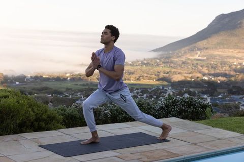 Man Practicing Yoga on Poolside Terrace with Mountain View
