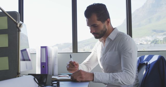 Focused Young Man Working at Office Desk with Scenic View - Download Free Stock Images Pikwizard.com