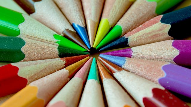 Close-up view of colored pencils arranged in a circular pattern with tips pointing inward. This can be used for educational material, art supplies advertisement, back to school promotions, creativity workshops, stationery-related content, and design inspiration visuals.