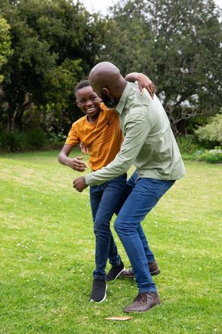 Father and Son Laughing and Playing Outdoors on Grass