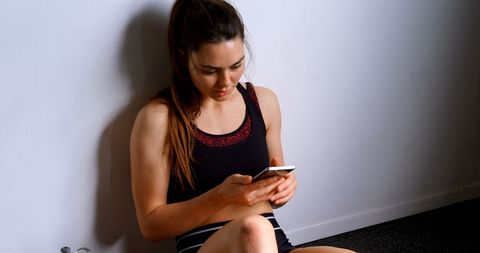 Fit Woman Using Smartphone in Gym Relaxed and Happy