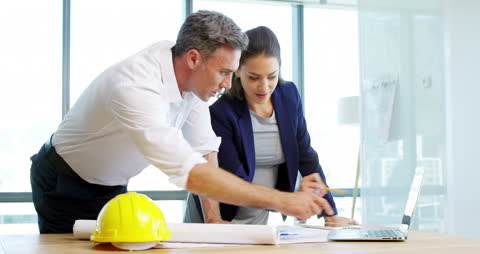 Architects Collaborating on Blueprint in Modern Office Space