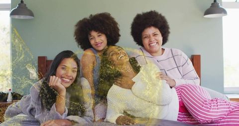 Four friends celebrating pregnancy at home wearing cozy loungewear, laughing and bonding