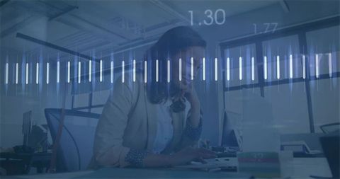 Female analyst typing at open-plan workstation with digital data overlay