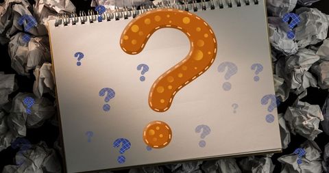 Colorful question marks over notebook with crumpled paper background