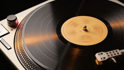 Spinning vinyl record on silver turntable with warm lighting and DJ tonearm