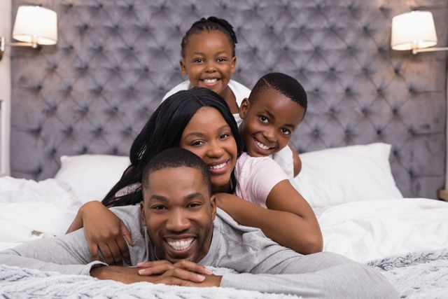 African American family enjoying time together, lying on bed and smiling. Perfect for advertising family-oriented products, promoting home comfort, or illustrating concepts of unity, love, and happiness.