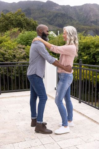 Mature african american man and senior woman embracing on mountain terrace balcony
