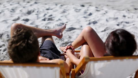 Couple Relaxing on Deck Chairs at Sunny Beach