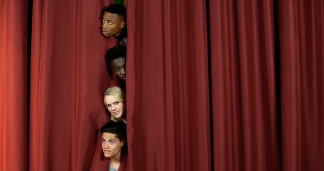 Diverse group of people peeking through an opening in a red curtain, showing curious and anticipatory expressions. Ideal for depicting theatre, teamwork, hidden talent, suspense or revealing new opportunities. Suitable for use in promotional materials, advertisements or event announcements focused on performing arts, diversity, curiosity or visual storytelling.