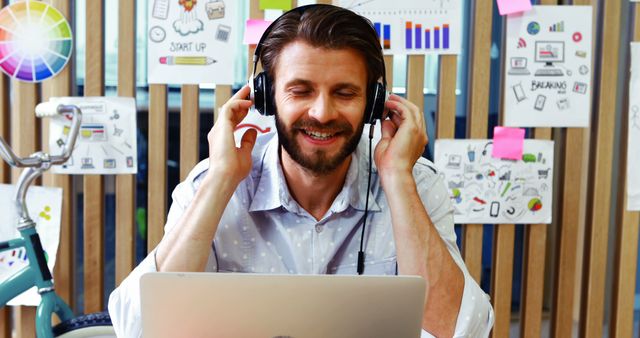 Young Man Working with Laptop and Headphones in Modern Office - Download Free Stock Images Pikwizard.com