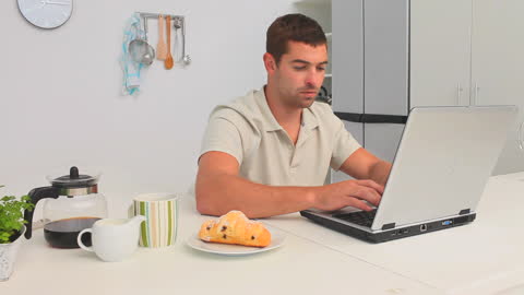 Casual Man Using Laptop in Modern Kitchen