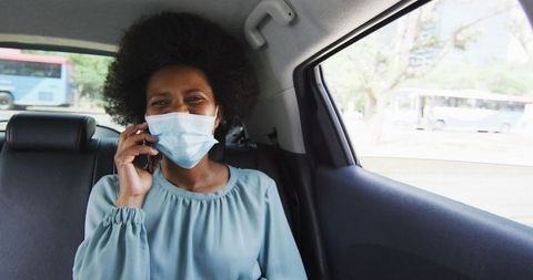 African American Businesswoman Wearing Mask on Phone in Car