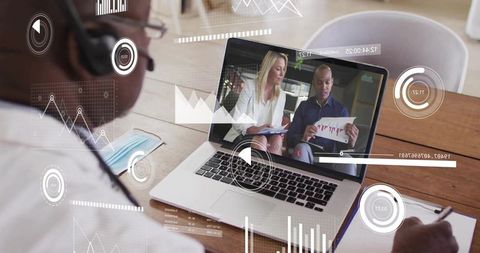Remote team presenting charts on laptop with digital HUD overlays and worker taking notes