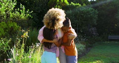 Loving Mother Embracing Children in Tranquil Garden Setting