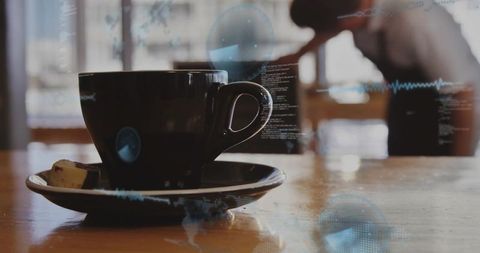 Dark ceramic coffee cup on wooden table with digital data overlays and blurred barista