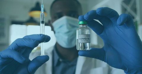 Scientist With COVID-19 Vaccine Vial and Syringe in Laboratory