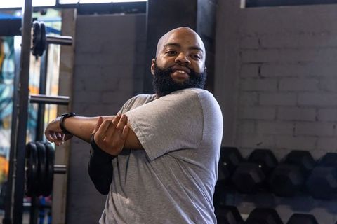 African american man stretching arm wearing compression sleeve in industrial gym workout