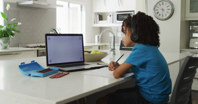 Happy biracial boy sitting at table using laptop with copy space and having online classes - Download Free Stock Photos Pikwizard.com