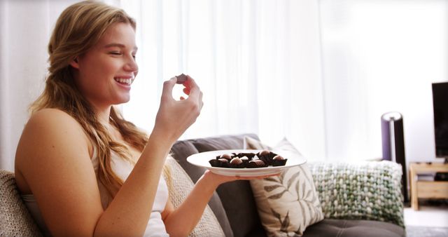 Woman eating chocolates in living room at home 4k