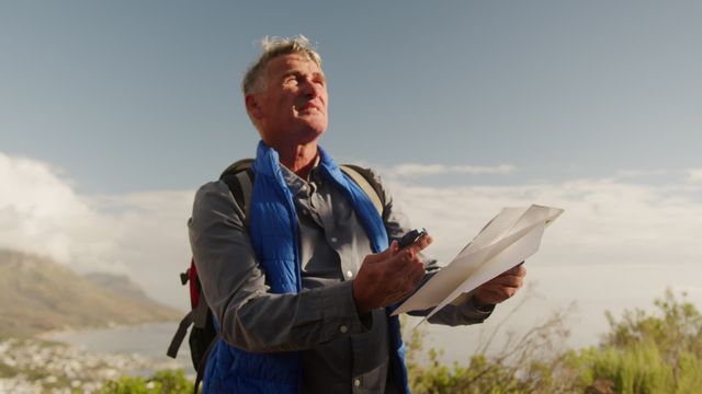 Senior Caucasian man explores the great outdoors with a map and compass, embracing an adventurous hiking trip. His joyful expression and active lifestyle represent enthusiasm and curiosity. Perfect for illustrating recreational activities, retirement pastimes, or nature travel promotions.