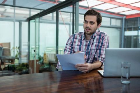 Young Professional Reviewing Documents in Modern Office