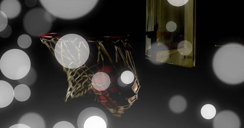 Basketball passing through worn net with glowing rim and moody bokeh court lights